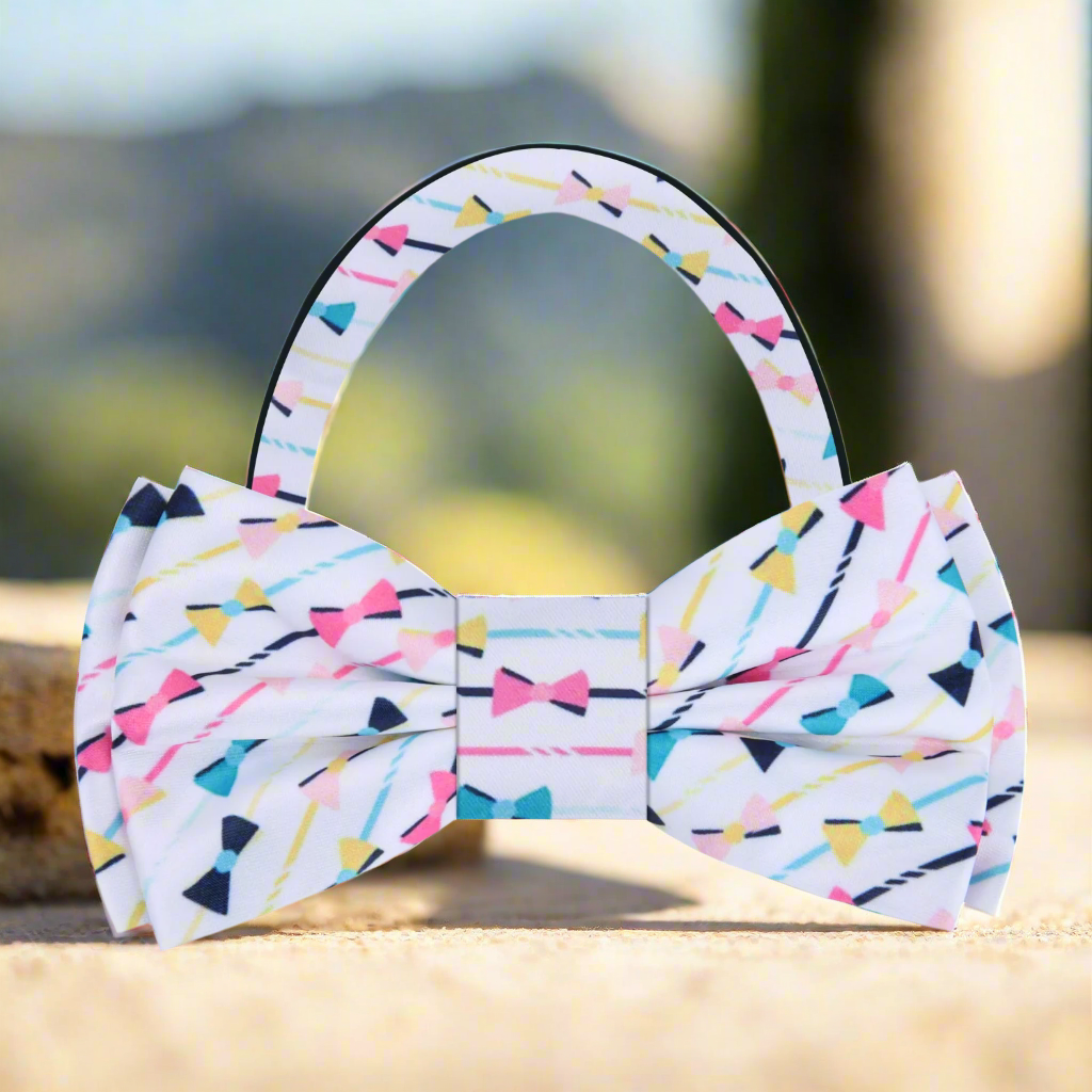 Close-up of a colorful silk bow tie with pink, blue, and yellow accents, ideal for casual weddings