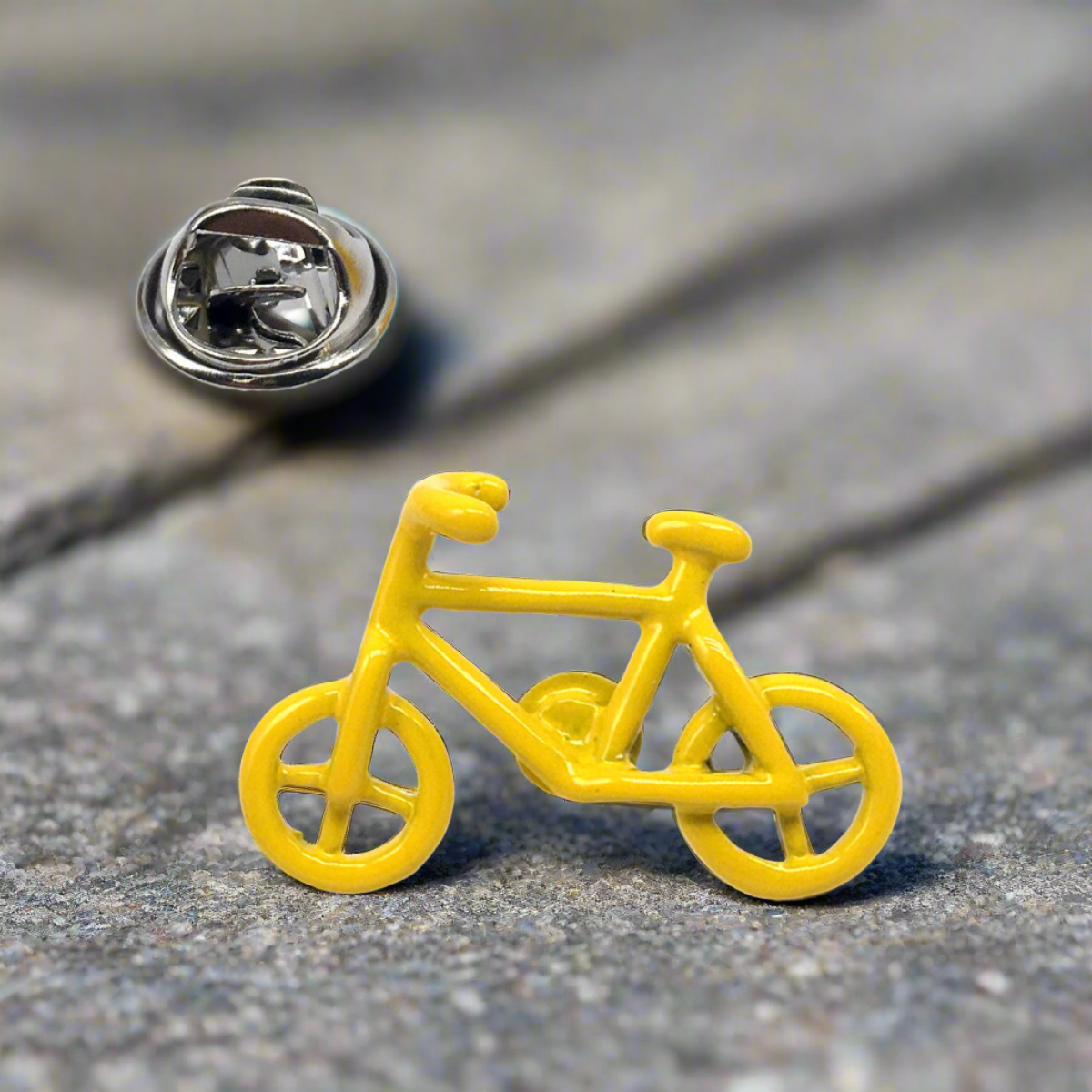 Close-up of yellow bicycle lapel pin against a light grey dress shirt.