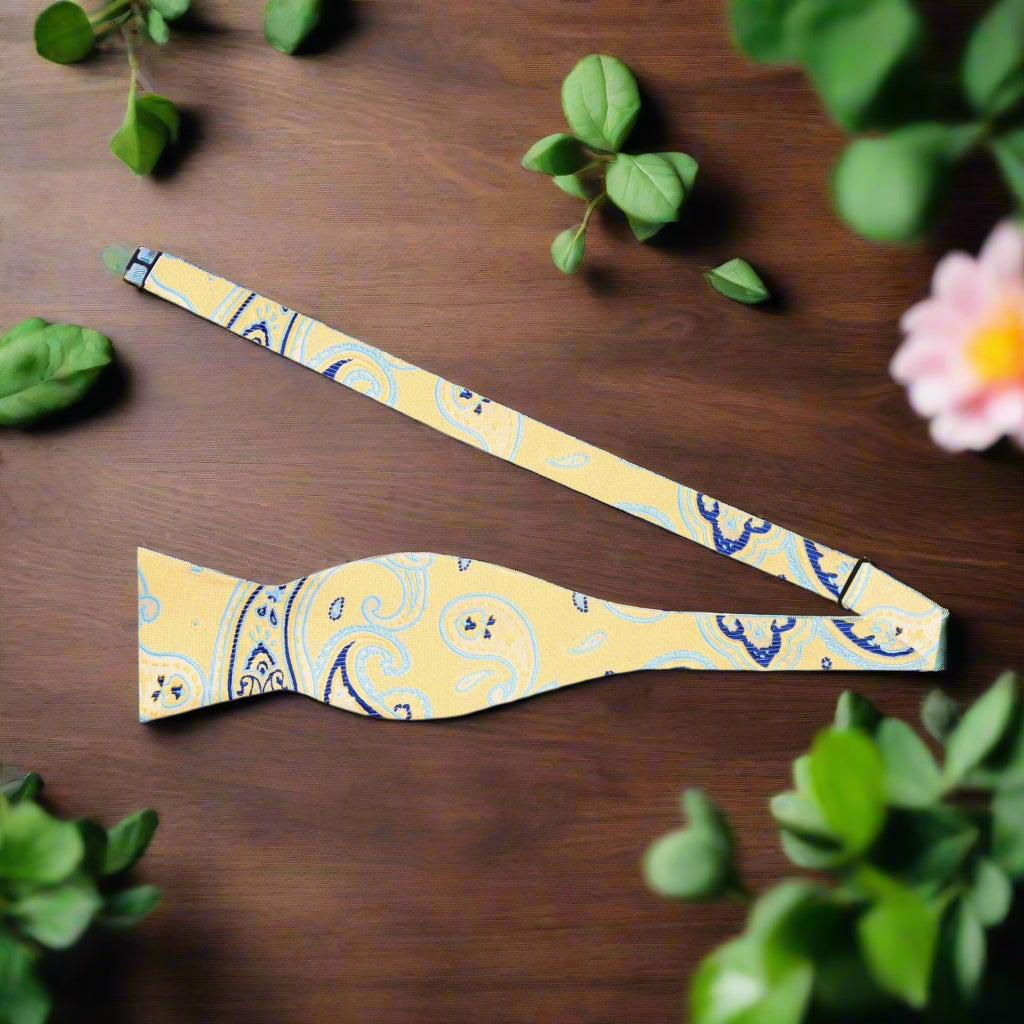 Self-tie paisley bow tie arranged elegantly with a light grey suit, showcasing its versatility.