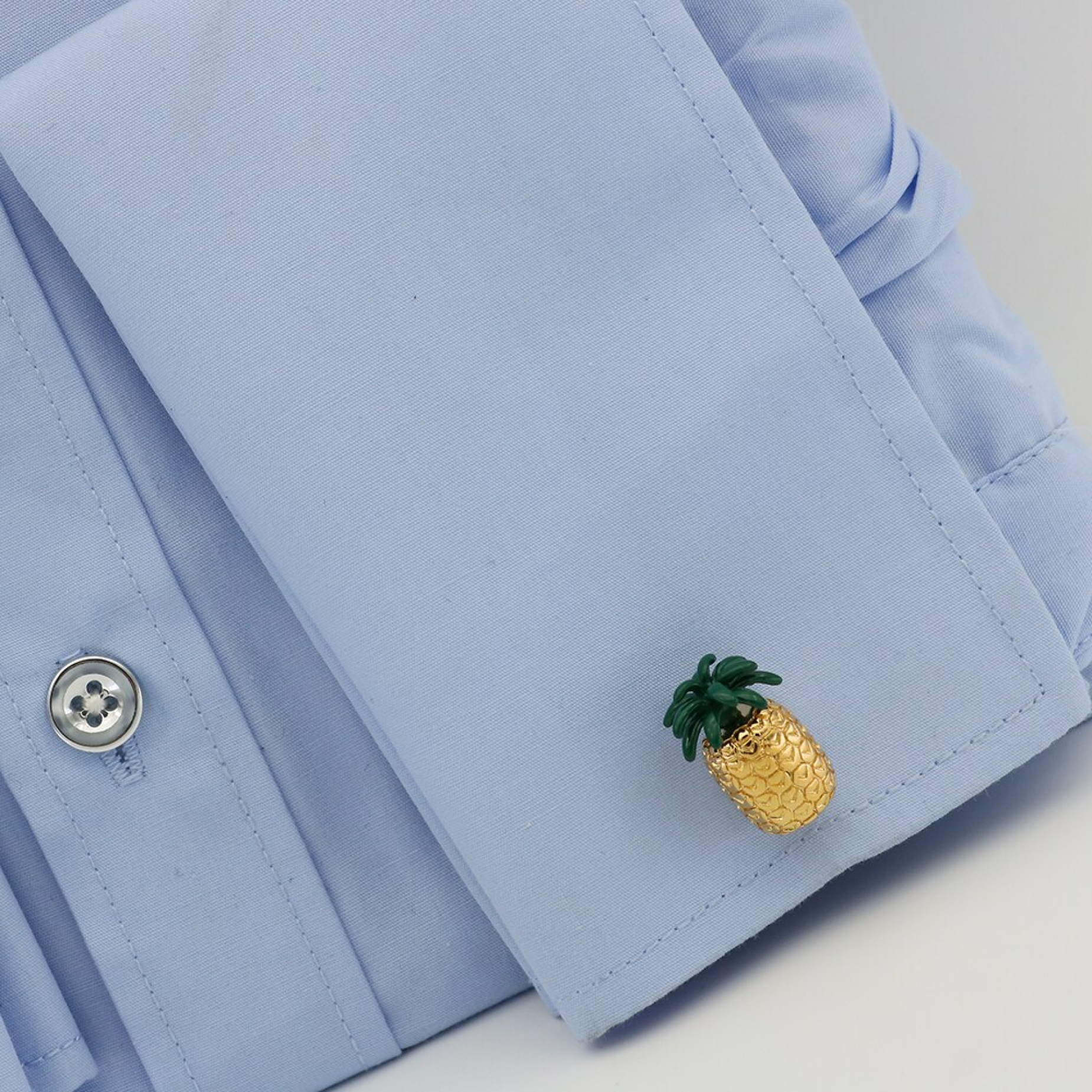 Close-up of tropical pineapple cufflinks with gold and green finish, perfect for summer events