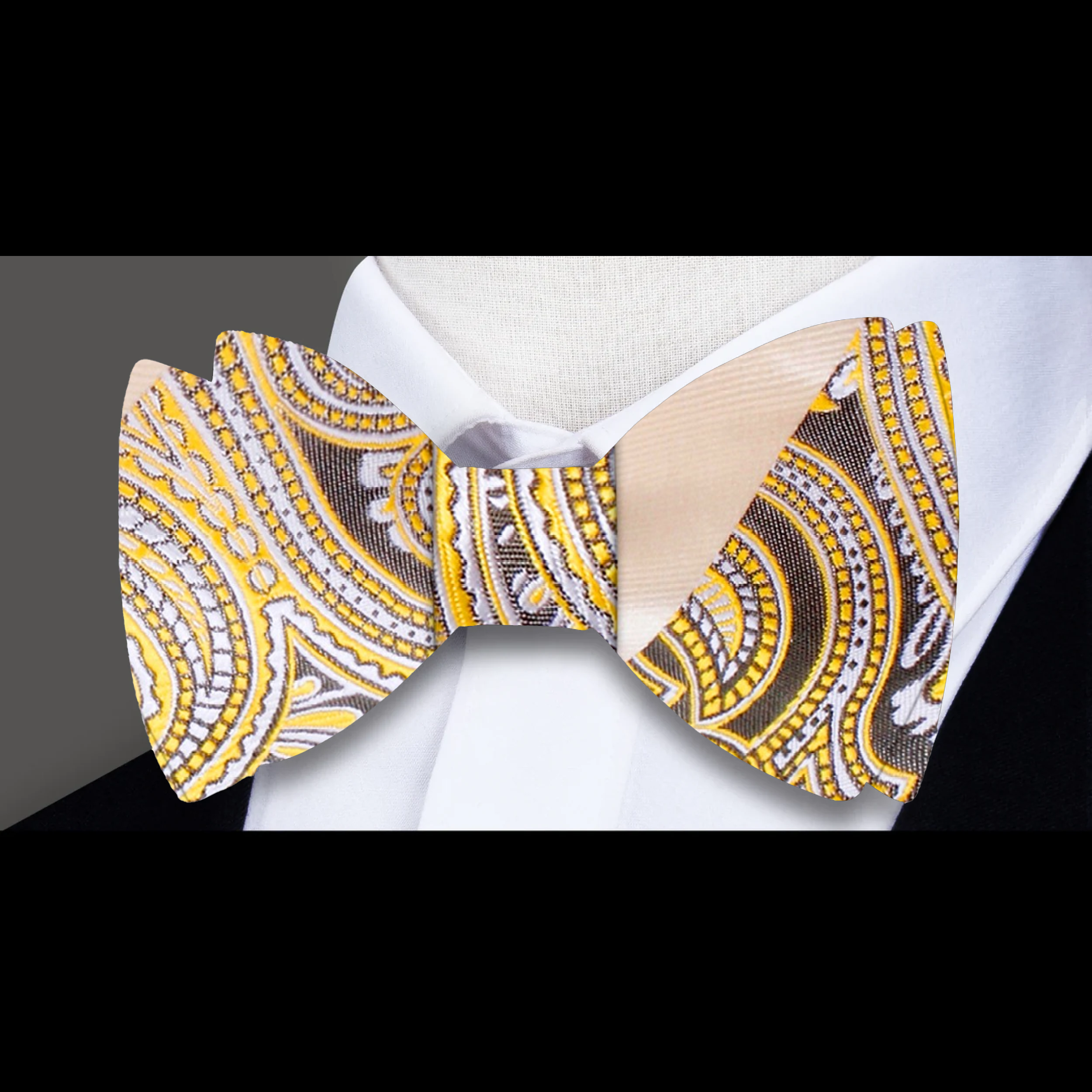 Close-up of yellow paisley silk bow tie with detailed pattern