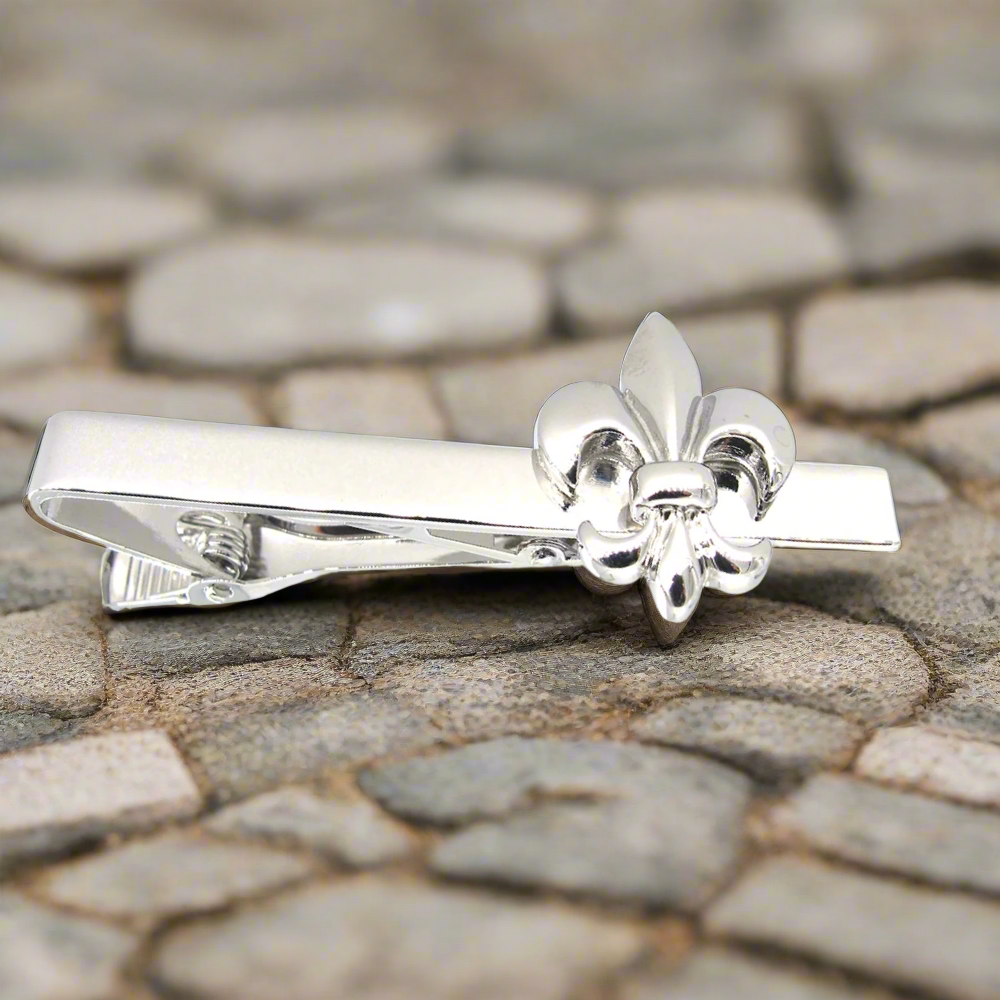 Chrome fleur-de-lis tie clip on a white dress shirt, highlighting its elegant design.