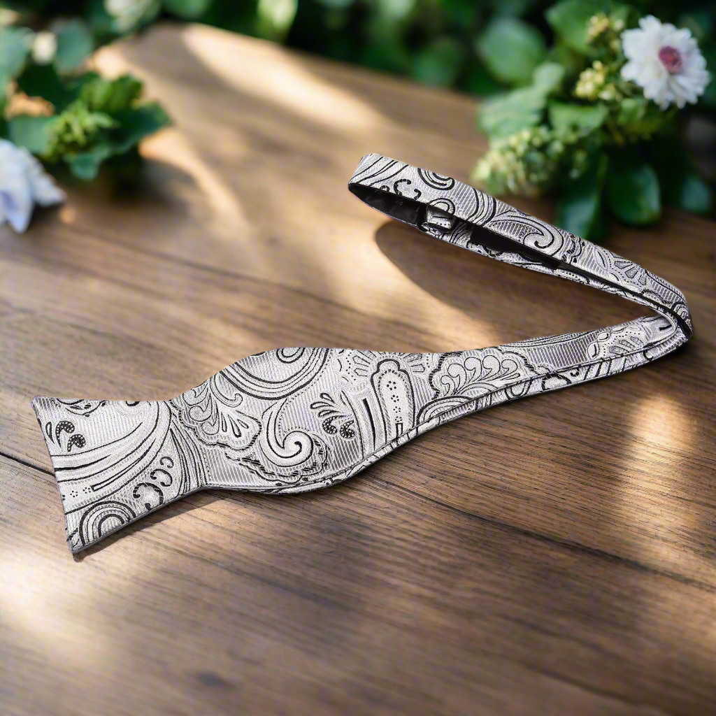 Close-up of paisley tie texture showing light grey silk and black embroidery
