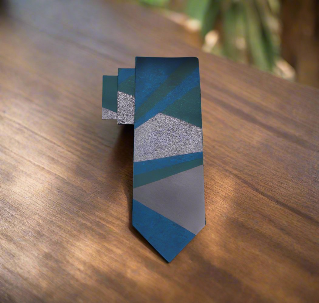 Teal silk necktie with an abstract pattern displayed on a black suit, ideal for wedding guests.