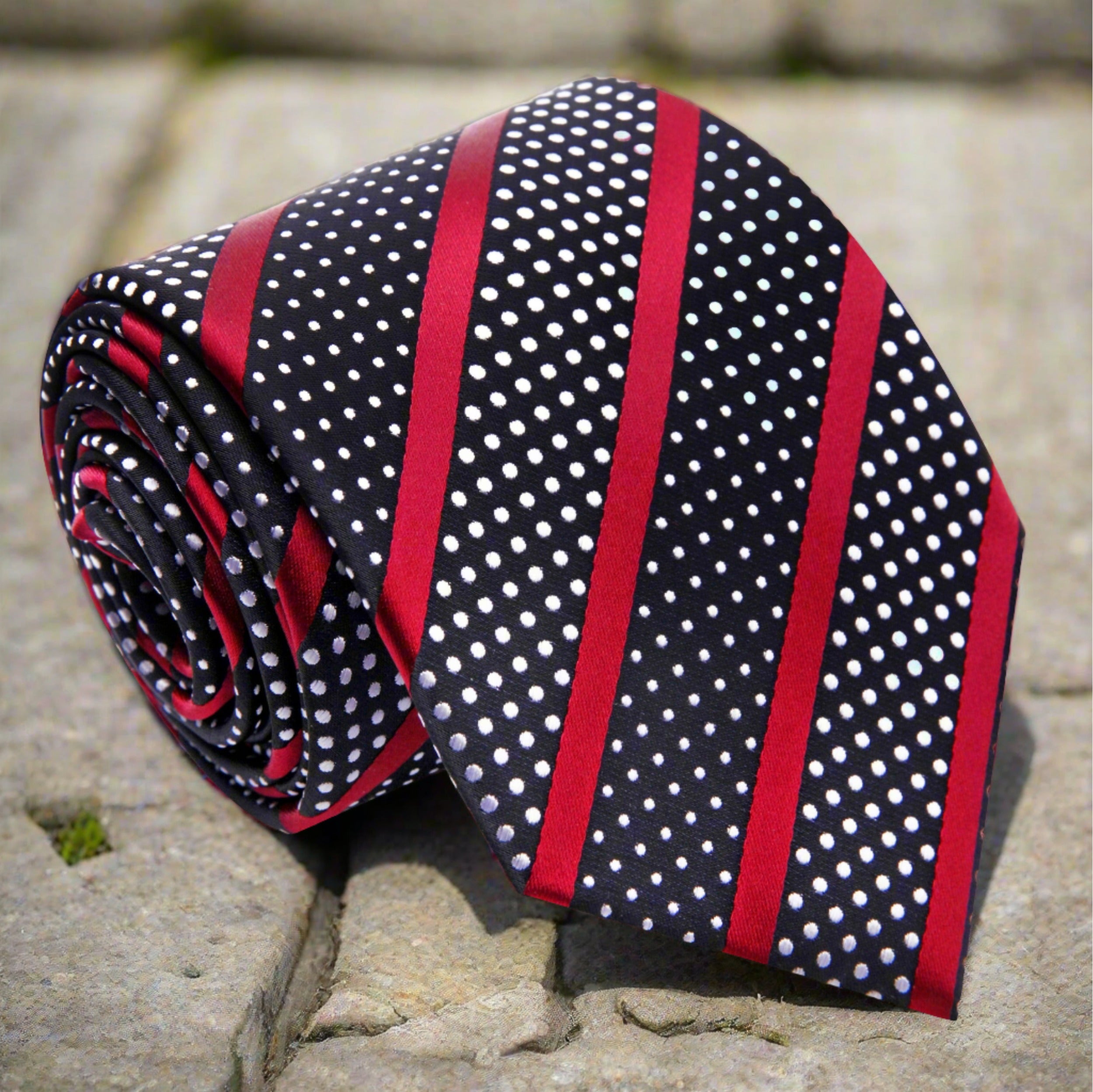 Close-up of black silk necktie with white dot pattern and red stripes for business attire
