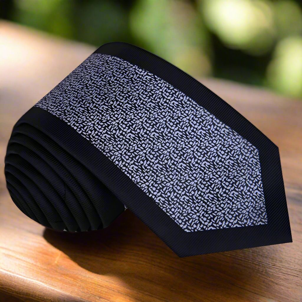 Black silk necktie with grey textured pattern lying flat for formal wear style