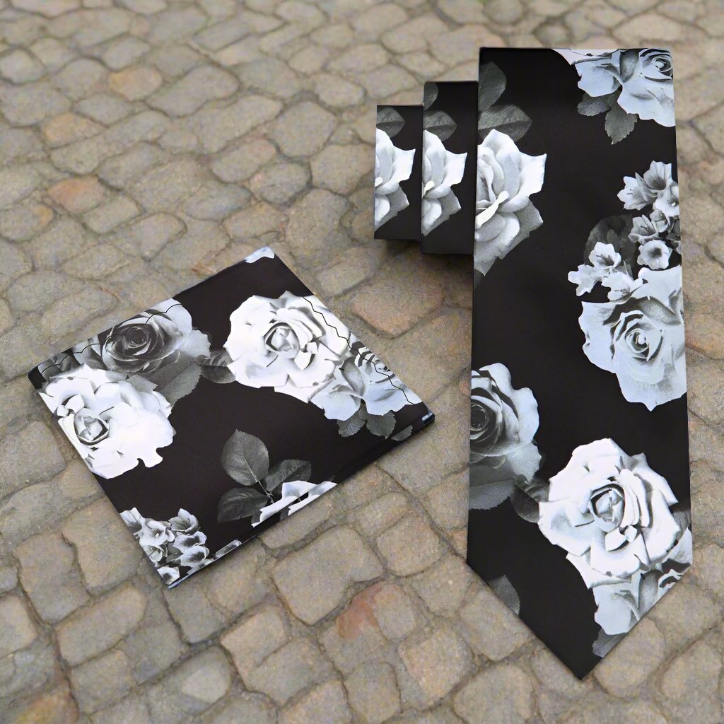 Elegant floral silk necktie displayed against a light grey suit, showcasing its intricate design of green leaves and pink roses.