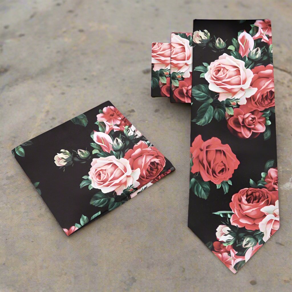 Elegant floral silk necktie displayed against a light grey suit, showcasing its intricate design of green leaves and pink roses.