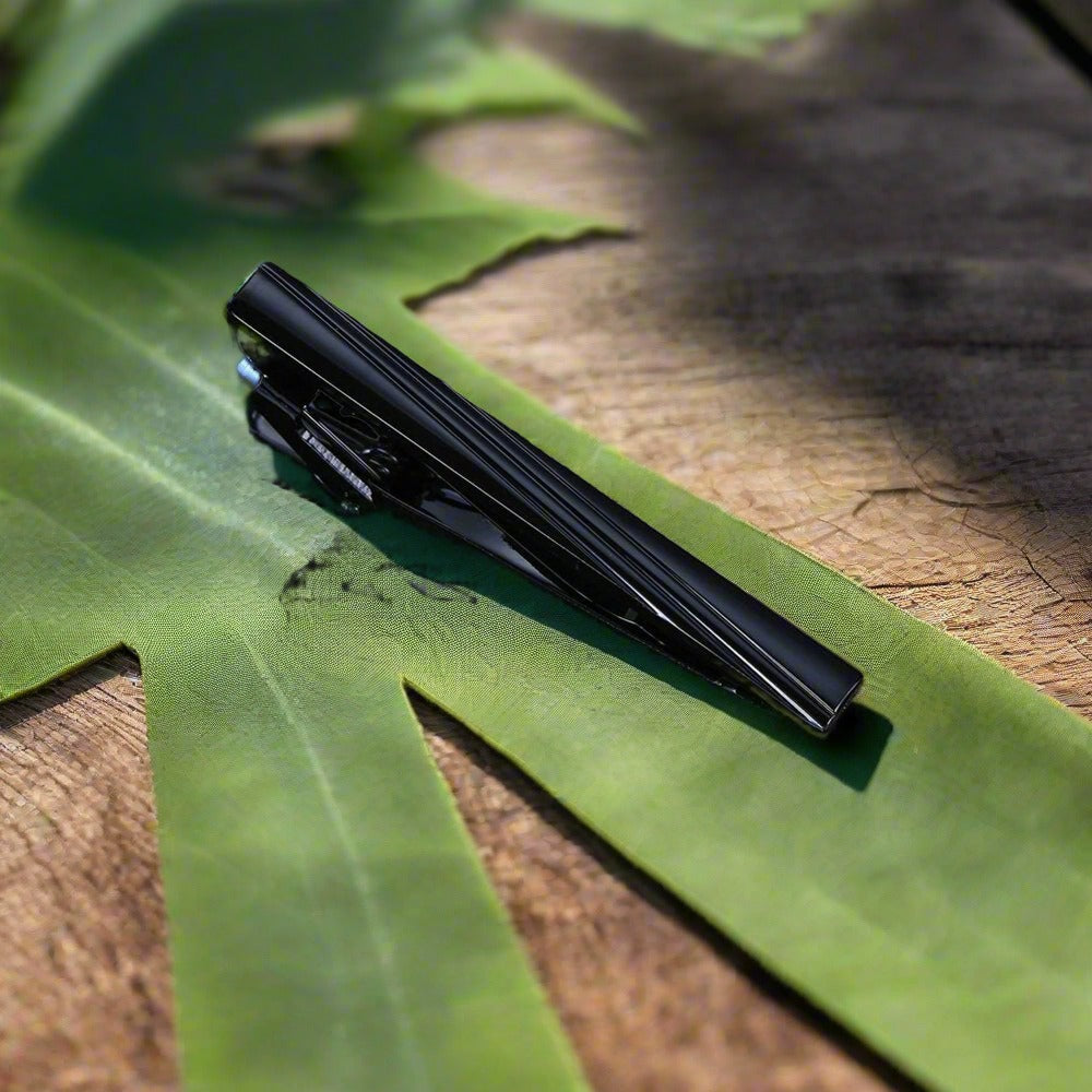 Elegant tie bar in mahogany with chrome floral design, perfect for formal occasions.