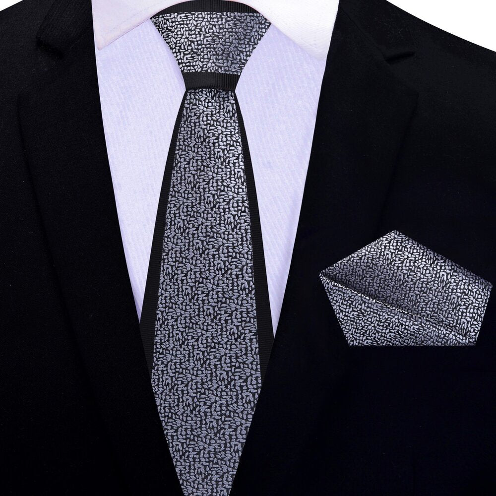 Black silk necktie with grey textured pattern lying flat for formal wear style