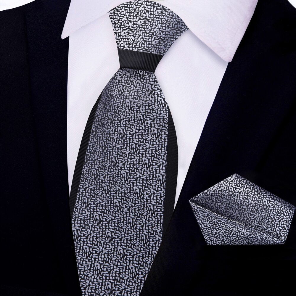 Man adjusting a black silk necktie with grey pattern for a professional look