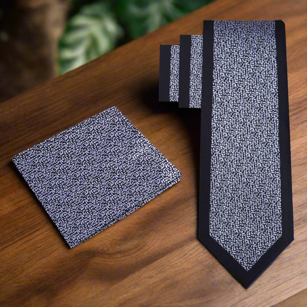 Man adjusting a black silk necktie with grey pattern for a professional look