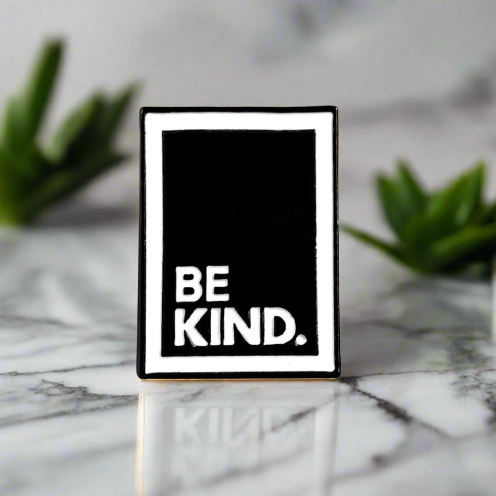 Close-up of motivational lapel pin on a white dress shirt showcasing the message 'Be A Nice Human'