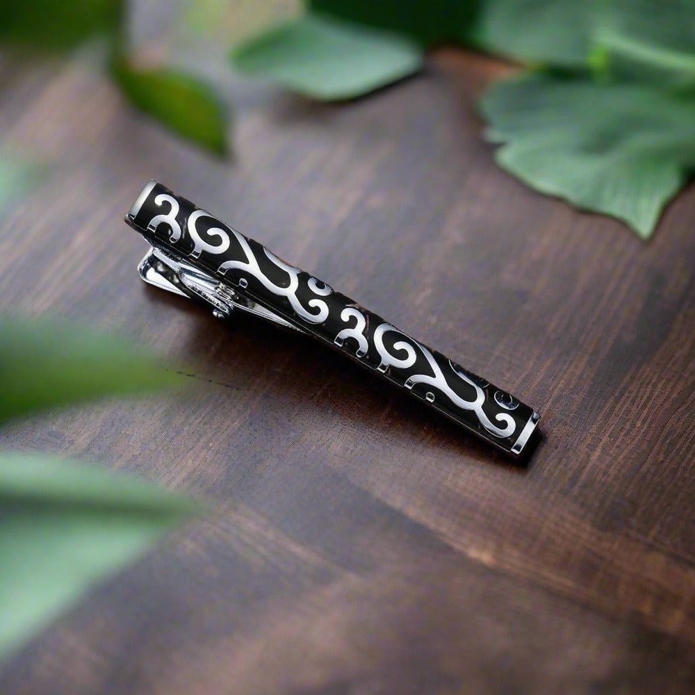 Elegant tie bar in mahogany with chrome floral design, perfect for formal occasions.