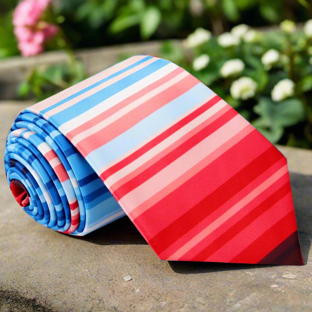 Men's silk necktie with gradient stripe pattern in red and blue, styled with a matching pocket square