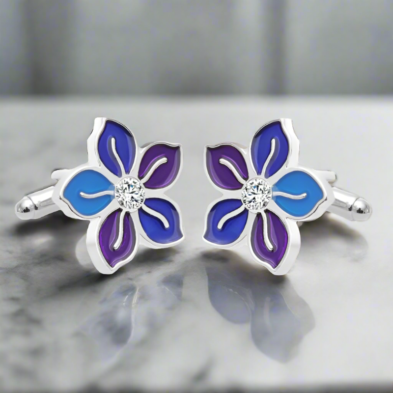 Close-up of flower cufflinks with chrome finish and blue-purple petals on white shirt cuff