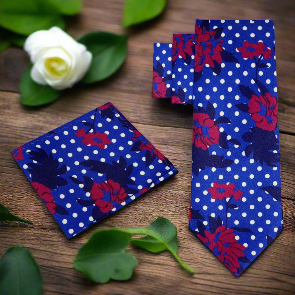 Close-up view of the silk ties intricate pattern featuring red hibiscus flowers and white dots against a blue background.