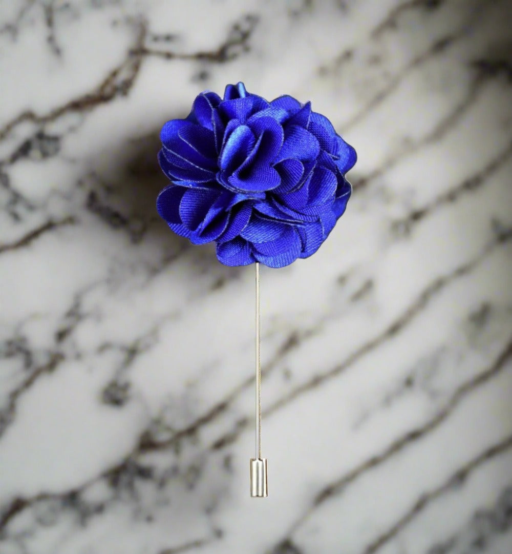 Close-up of teal flower lapel pin on a mens suit collar for wedding guest look