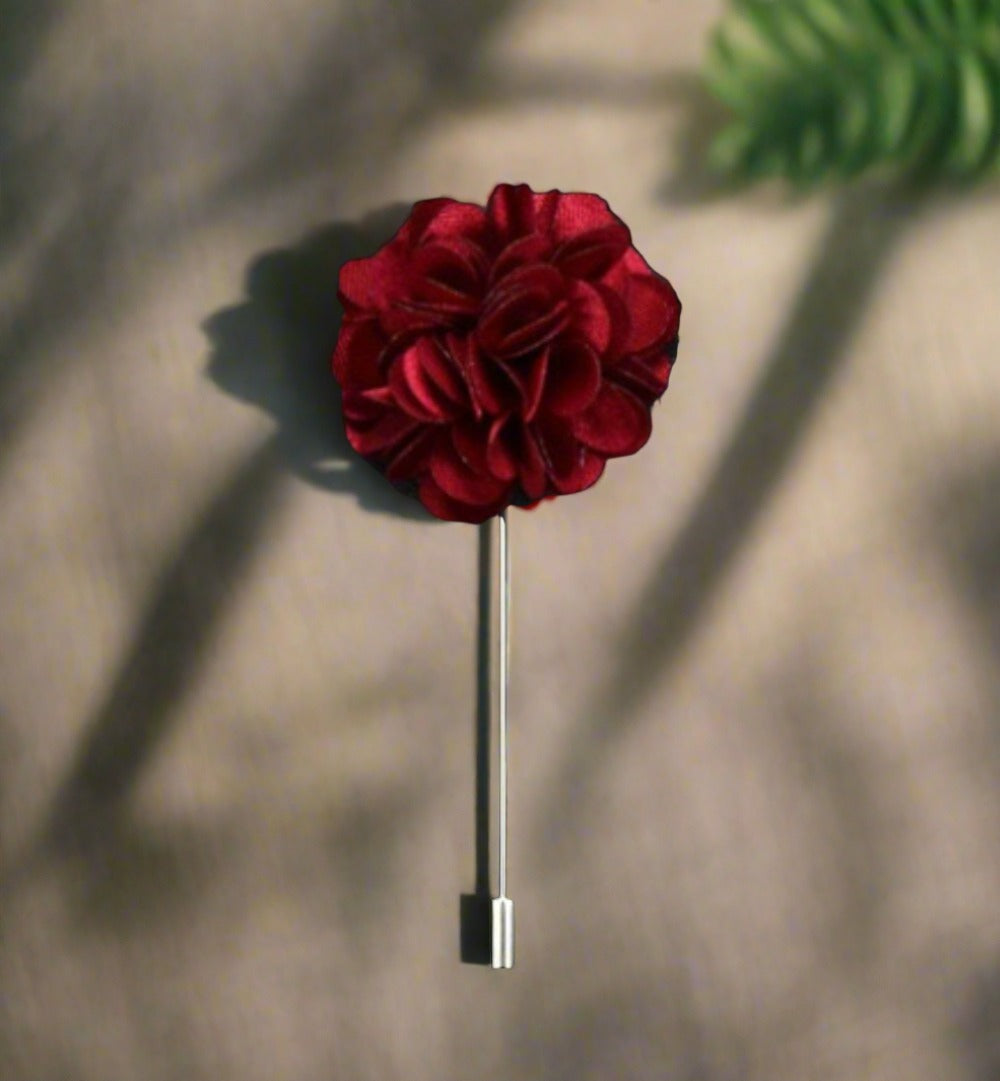 Close-up of teal flower lapel pin on a mens suit collar for wedding guest look