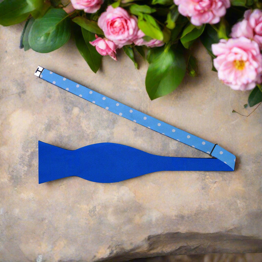 Close-up of reversible silk bow tie with white dots and solid blue sides, showing detailed fabric texture
