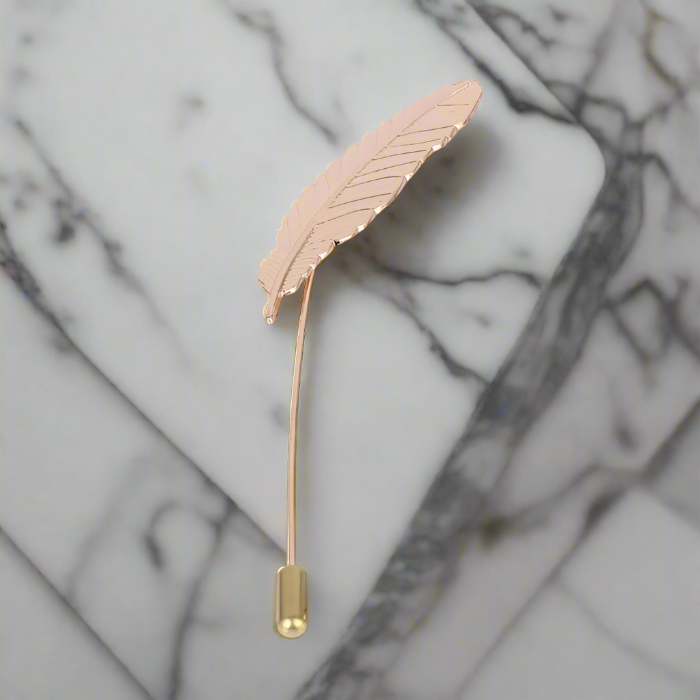Elegant gold feather lapel pin displayed on a navy suit, showcasing its luxurious design.