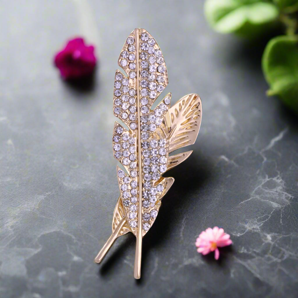 Elegant gold feather lapel pin with sparkling stones, ideal for formal wear.