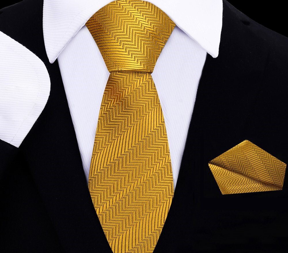 Golden amber silk tie and pocket square set displayed on a wooden table, highlighting the luxurious texture.