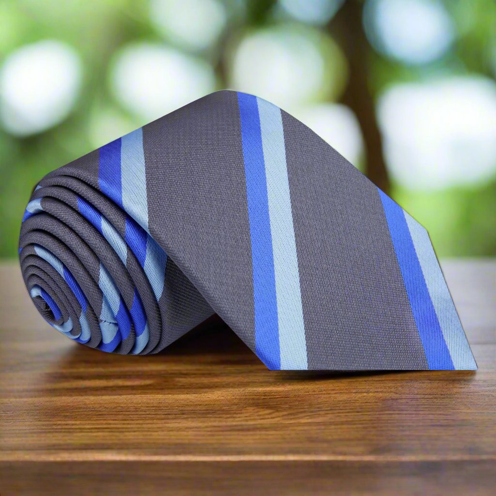 Elegant silk necktie with blue and grey stripes laid out on a white shirt