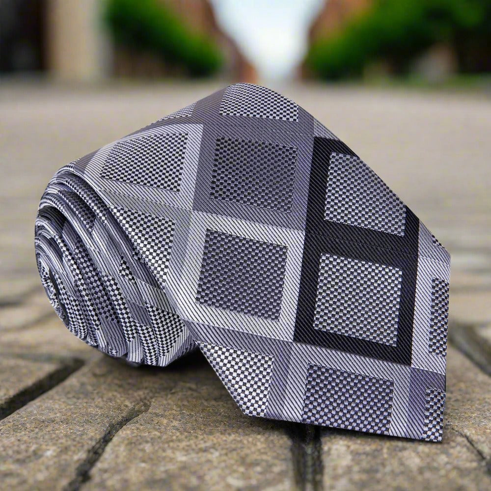 Elegant mens geometric silk necktie with dark grey and black pattern on a models neck
