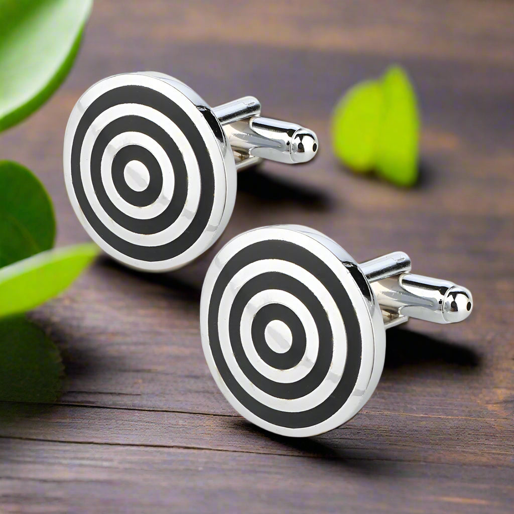 Chrome and black bullseye cufflinks placed on a white dress shirt, showcasing their elegant design.