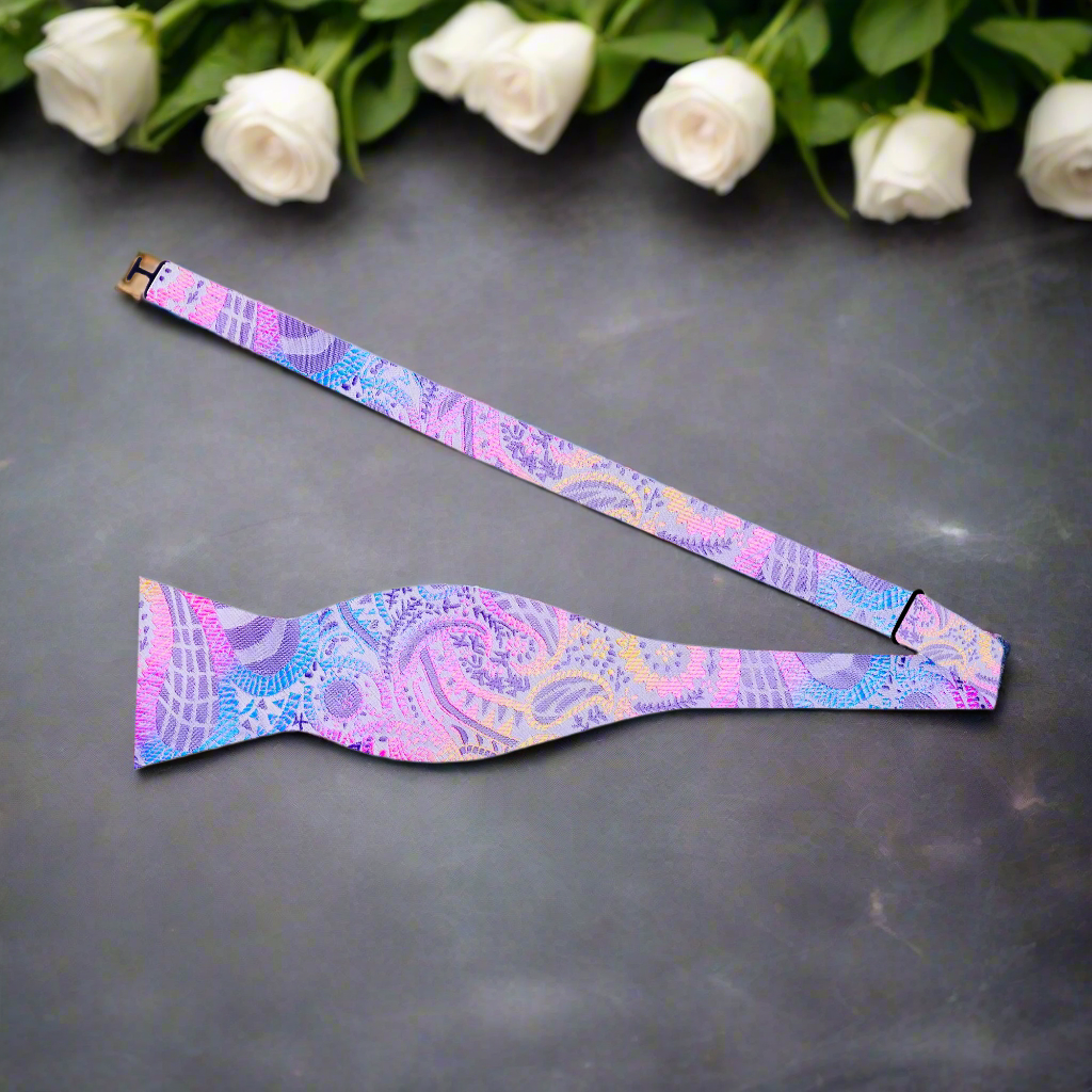 Man wearing a pastel paisley bow tie at a summer outdoor wedding