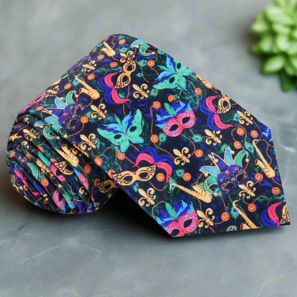 Close-up of Mardi Gras mask tie showing silk texture and vibrant pink, blue, and green masks against a black background