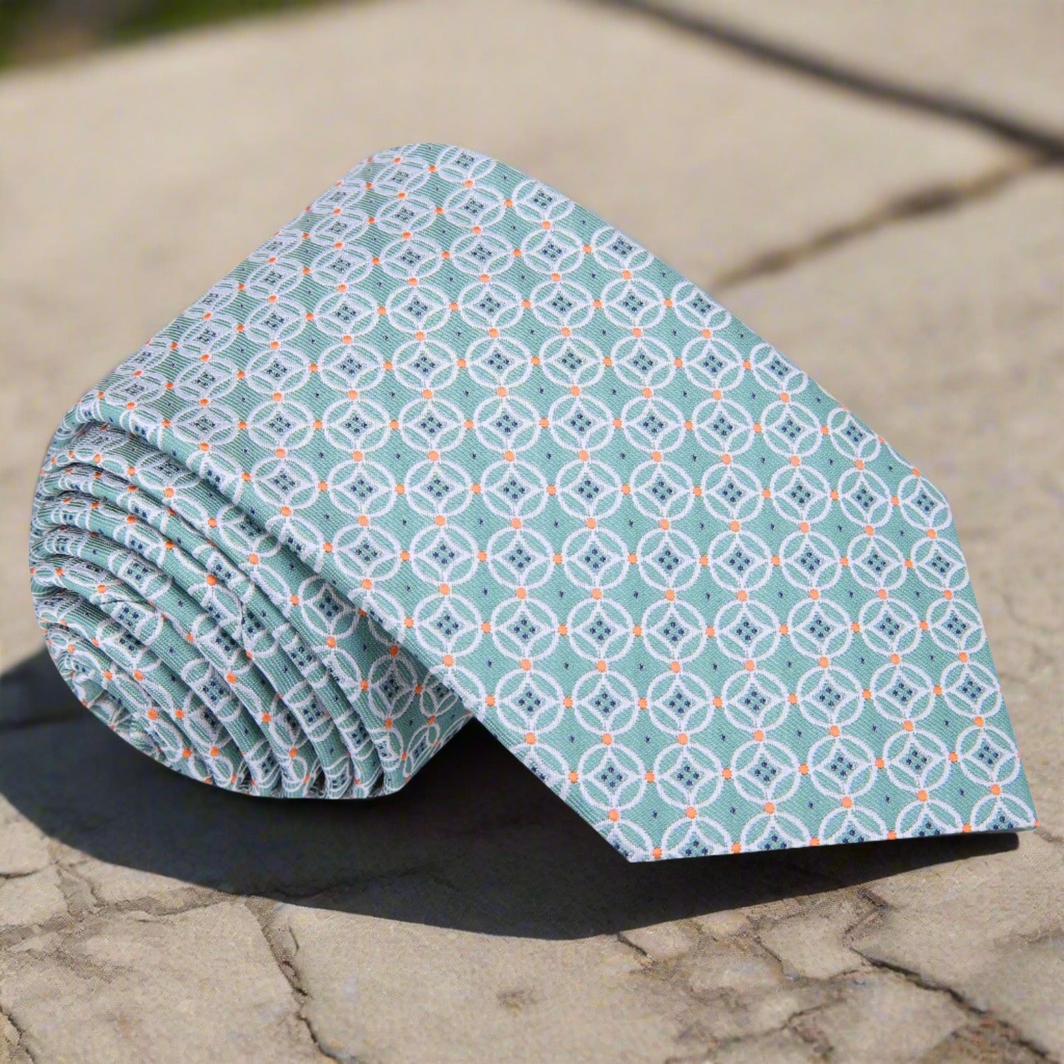 Close-up of geometric pattern silk necktie in mint green and orange for weddings