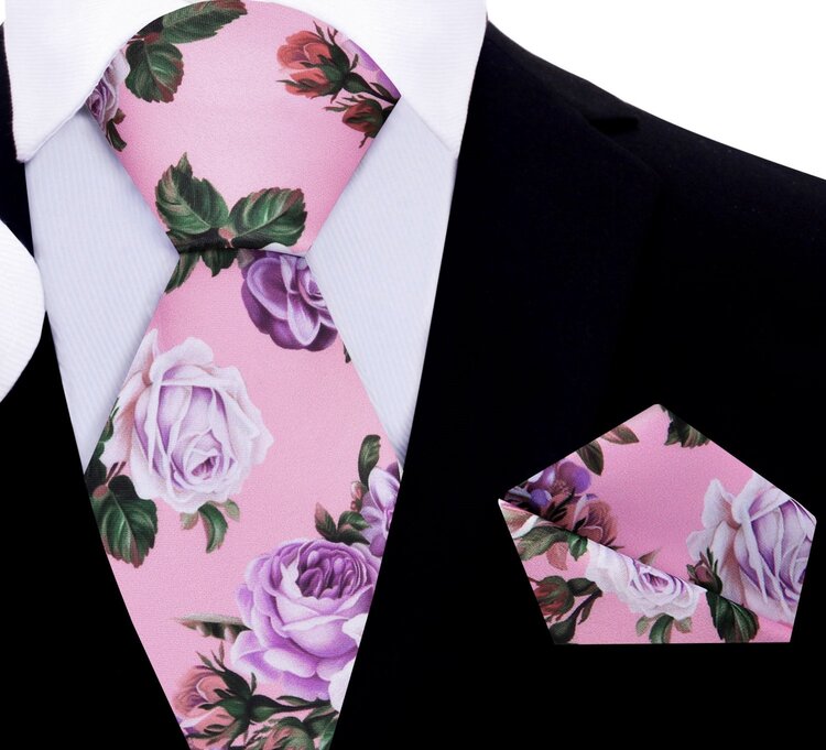 Elegant floral silk necktie displayed against a light grey suit, showcasing its intricate design of green leaves and pink roses.