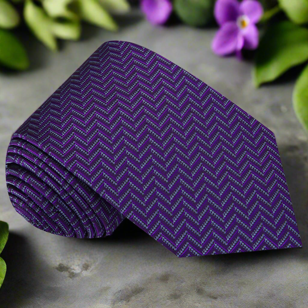 Close-up of the elegant purple and grey silk necktie showcasing its herringbone pattern.
