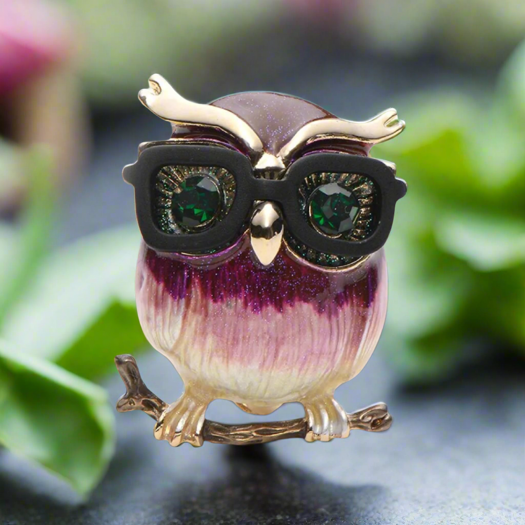 Front-facing owl lapel pin with brown speckles and miniature glasses, styled on a navy suit