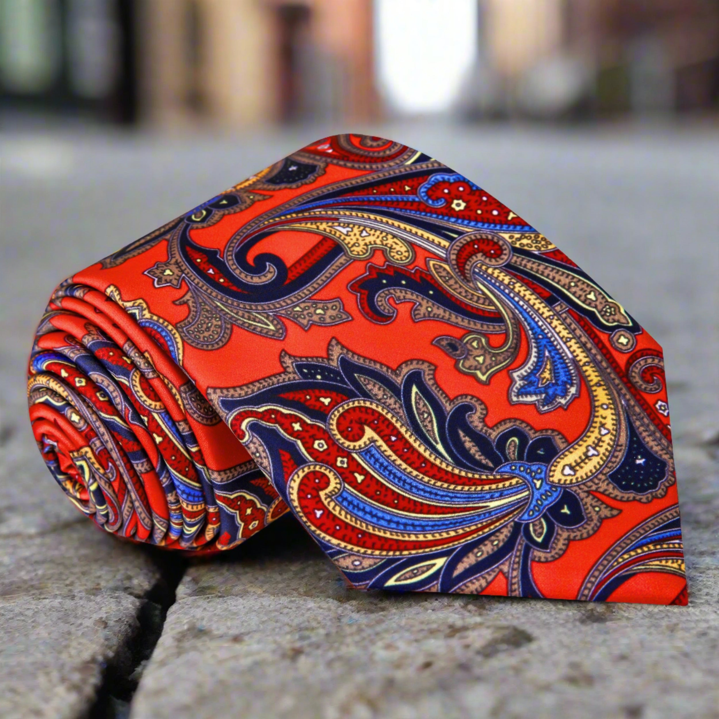 Close-up of the Monarch paisley silk tie showing its vibrant red, blue, and yellow pattern