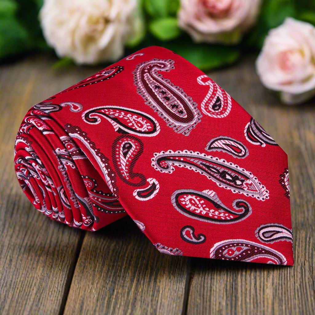 Red paisley silk tie displayed on a white dress shirt, showcasing its vibrant pattern and elegance.