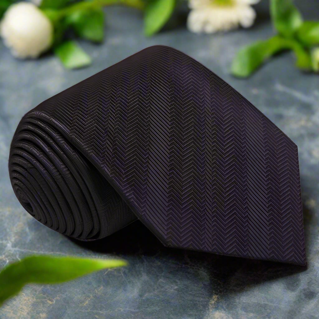 Elegant black silk necktie draped over a formal suit, showcasing its sleek design.