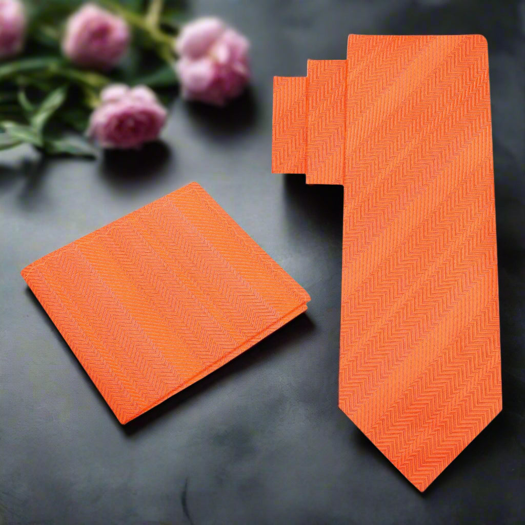 Close-up of orange necktie with pocket square — elegant silk texture