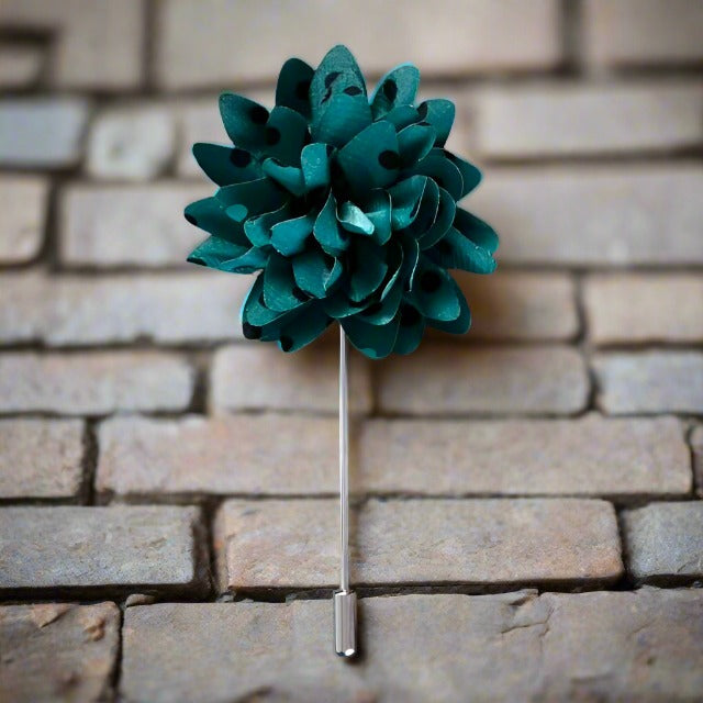 Teal lapel flower pin with black polka dots, showcasing its vibrant colors and elegant design.