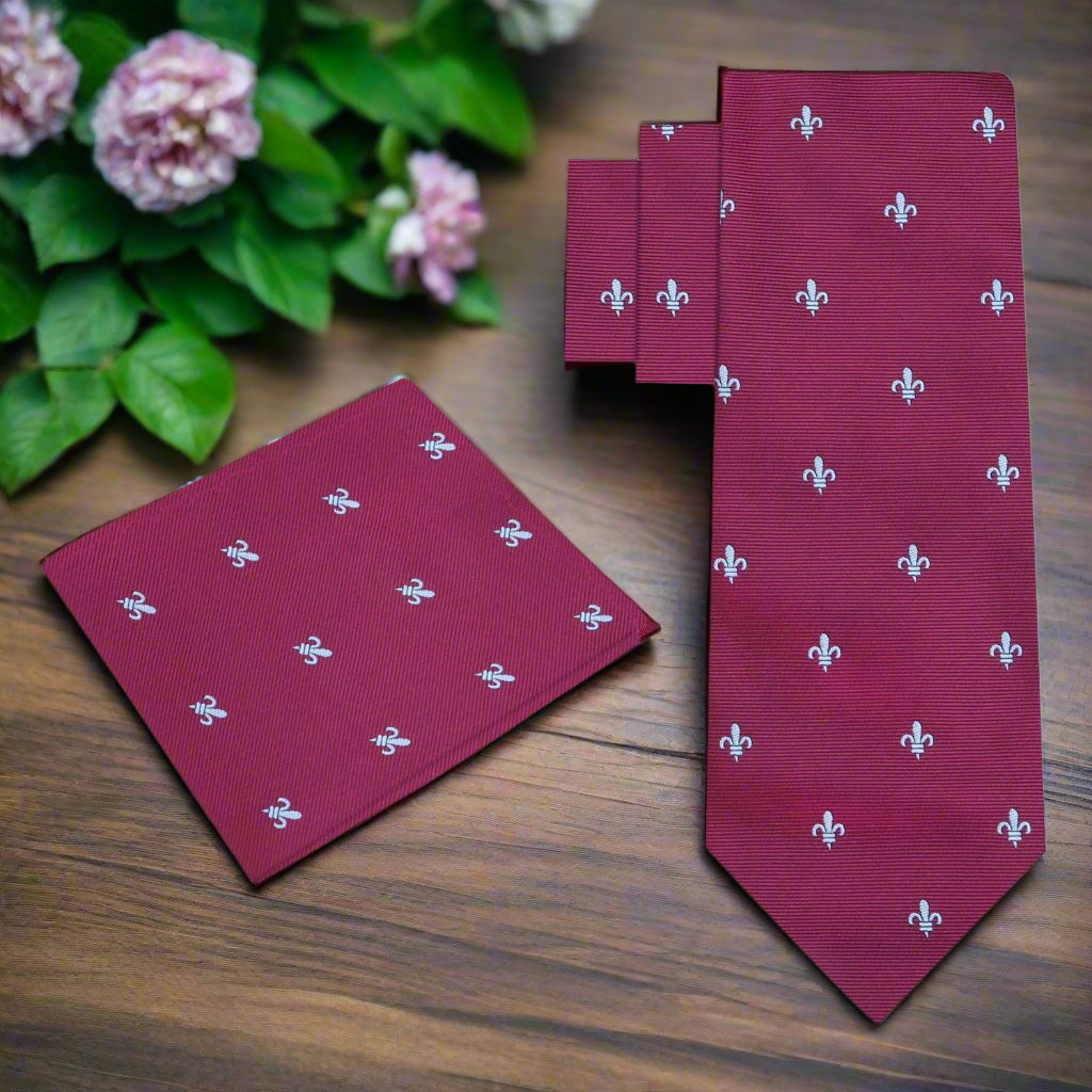 Elegant deep red silk necktie with fleur-de-lis design, displayed on a white shirt.