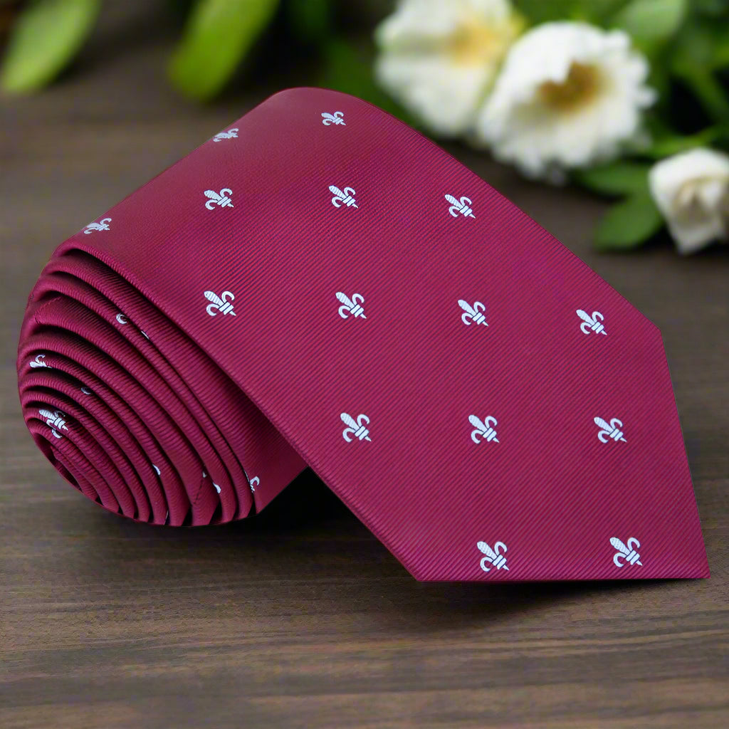 Elegant deep red silk necktie with fleur-de-lis design, displayed on a white shirt.