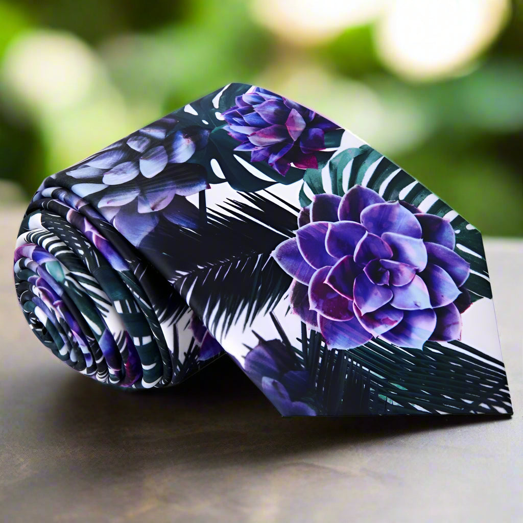 Close-up of a floral silk tie with large leaf and flower pattern in white, green, purple, and black