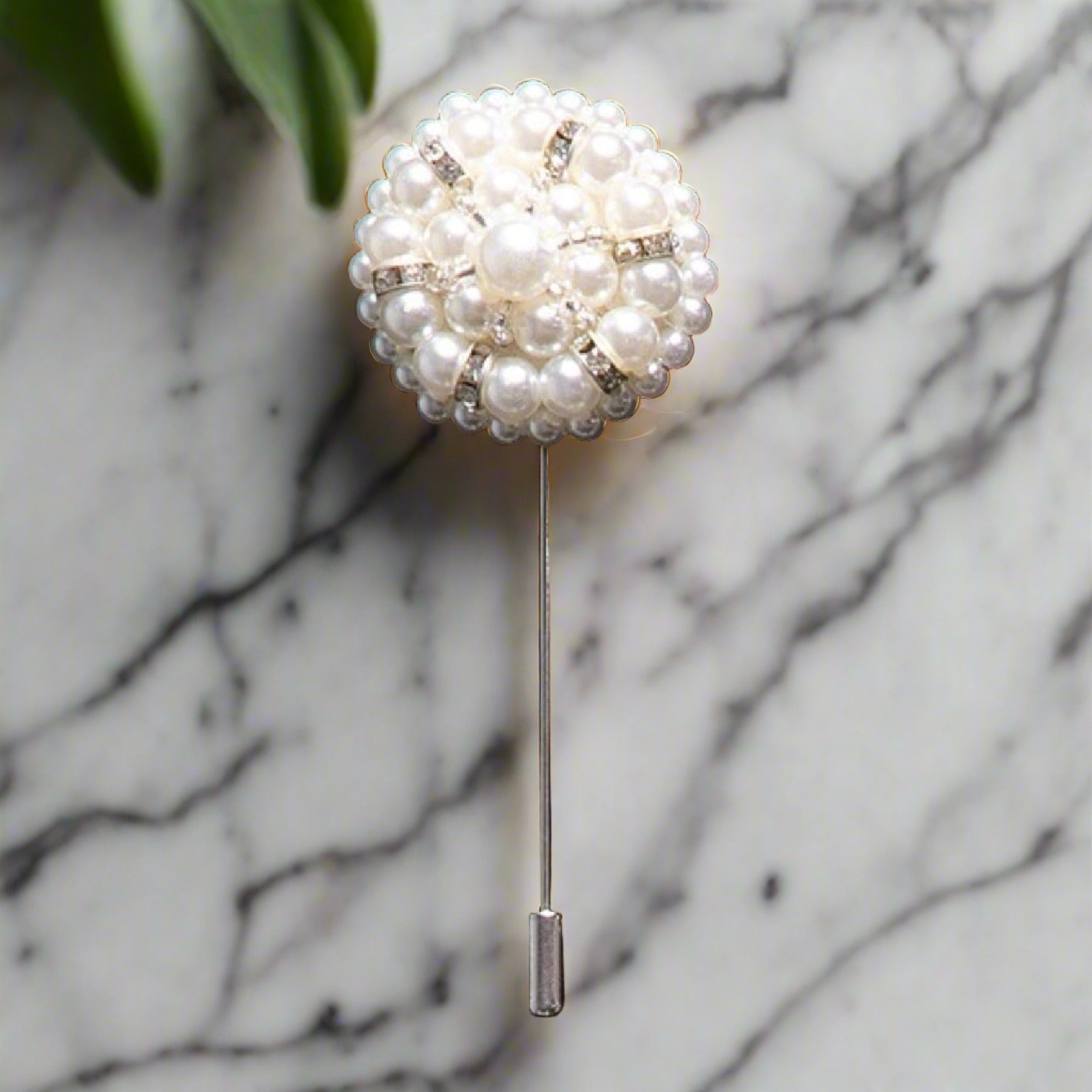 Close-up of elegant pearl cushion lapel pin on a tailored blazer.