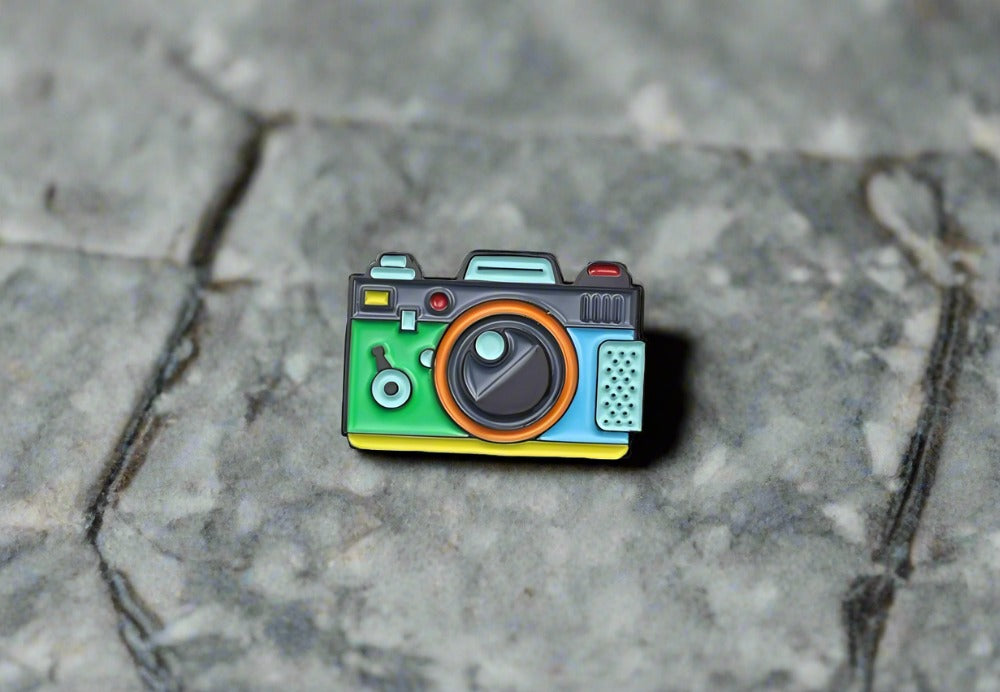 Front view of colorful camera lapel pin on a white shirt