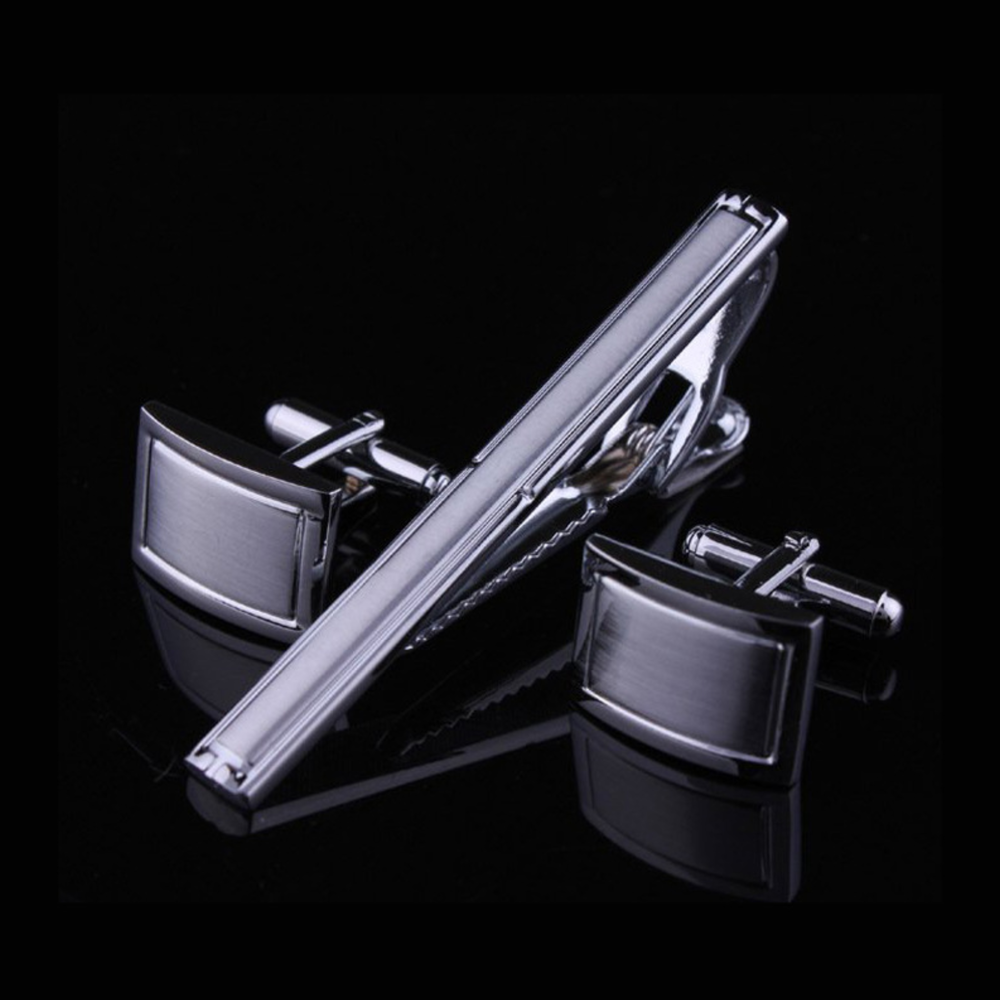 Close-up of silver tie bar and cufflinks angled on a dress shirt